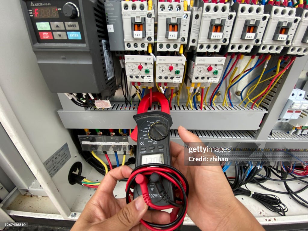 Human hand measuring ampere with meter